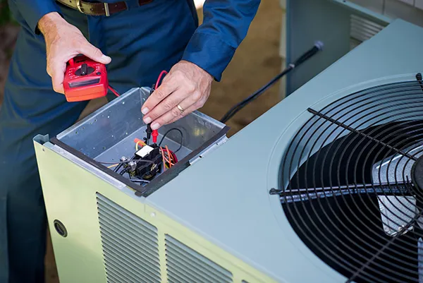 An HVAC technician is fixing an air conditioning condenser.