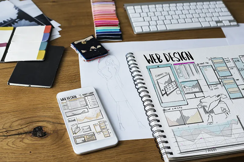 A photo of a desk with color pallets and a notebook labeled web desgin